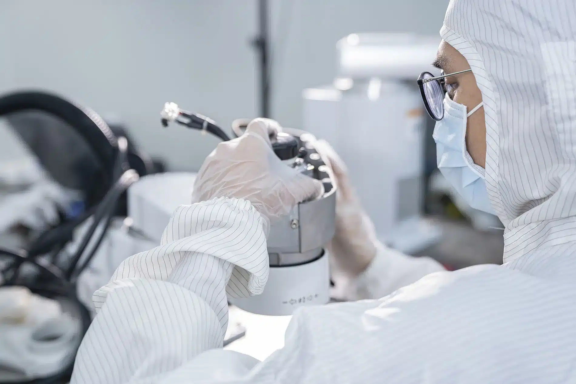 Technician assembling precision components in cleanroom for semiconductor consumables supplier